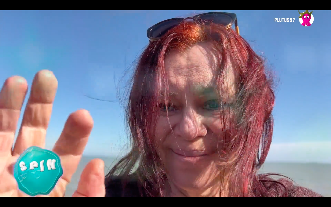 A white woman in her 60’s stands surrounded by sea water, looking up at three pearls above her head. A fuschia pink octopus tentacle is wrapped around her body.